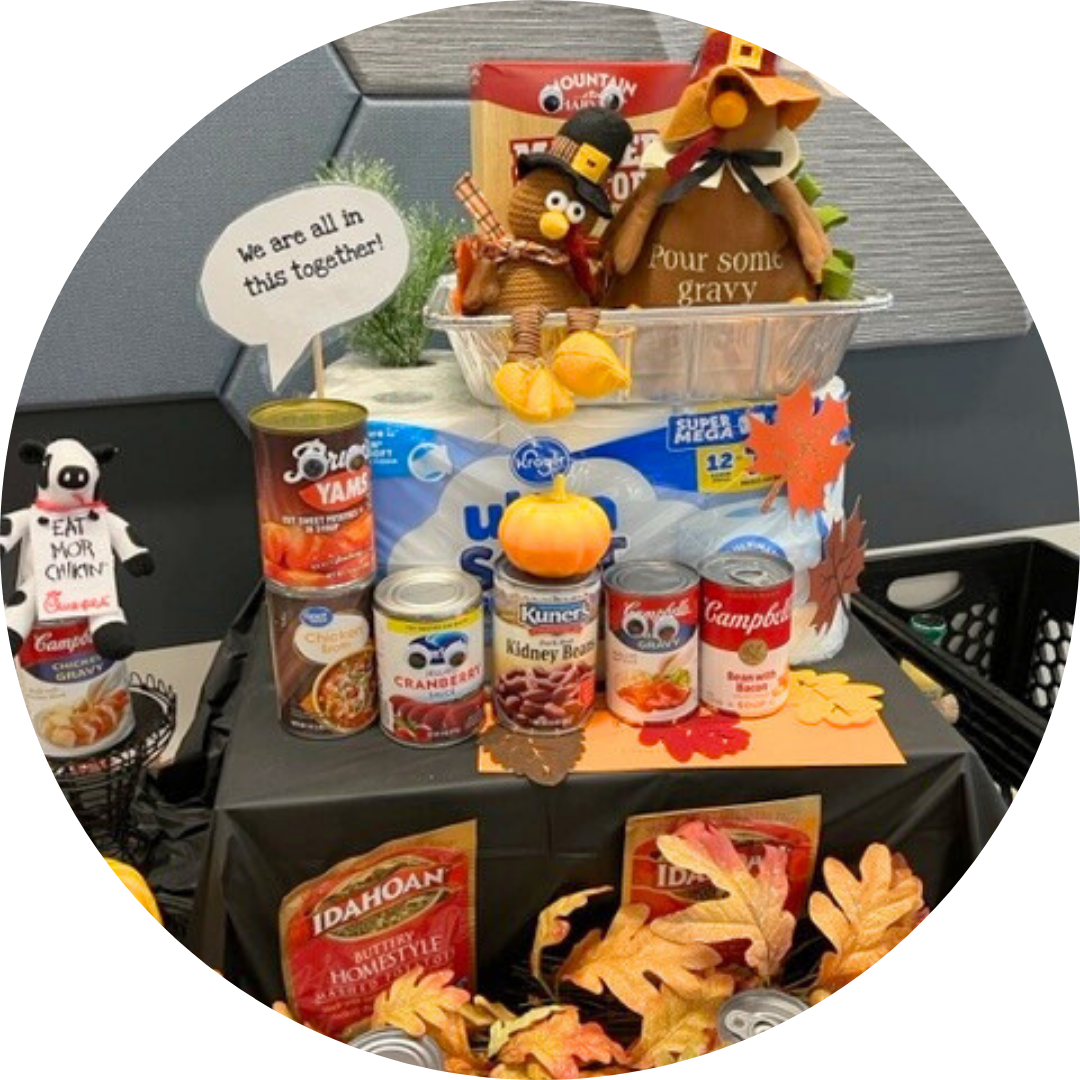 A display of canned and boxed food with toy turkeys and fake autumn leaves promoting a food drive for FISH.